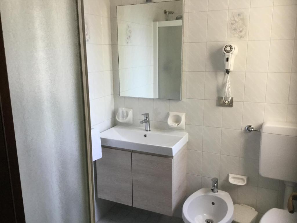 une salle de bain avec un lavabo, des toilettes et un miroir dans l'établissement Acapulco Beach, à Lido di Jesolo