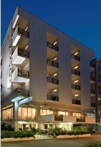 un grand immeuble d'appartements éclairé dans l'établissement Hotel Niagara, à Cattolica