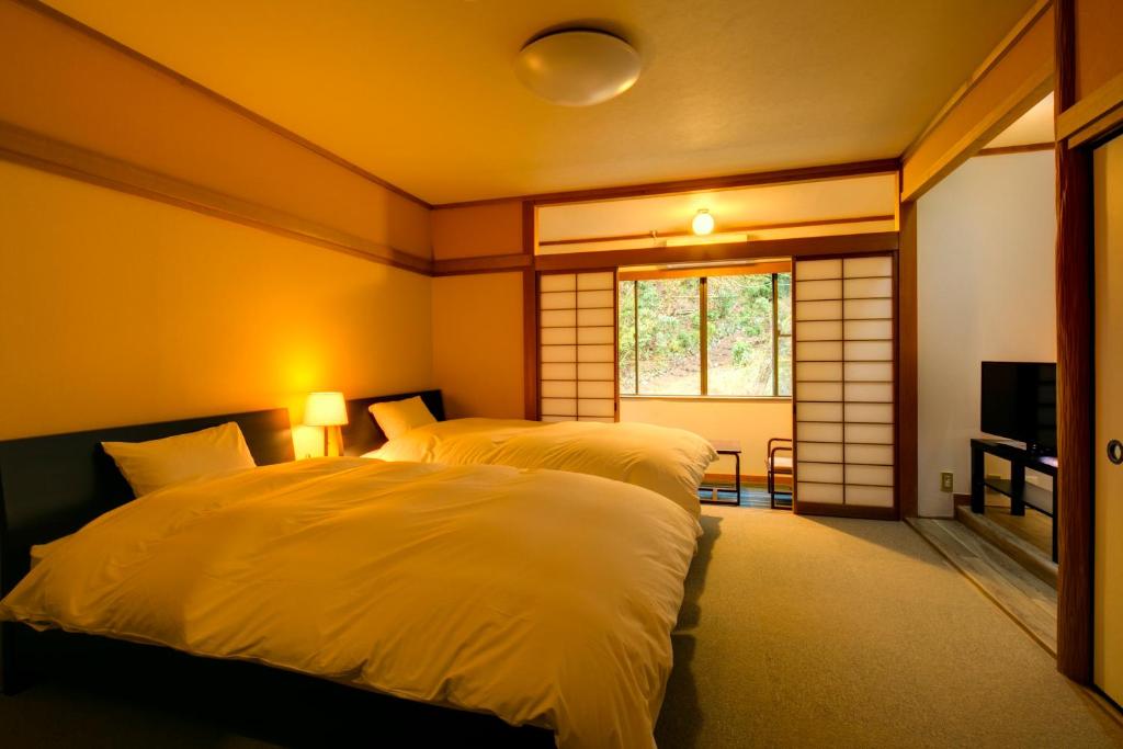 une chambre avec deux lits et une fenêtre dans l'établissement Yugawara-Onsen Komachikan, à Yugawara