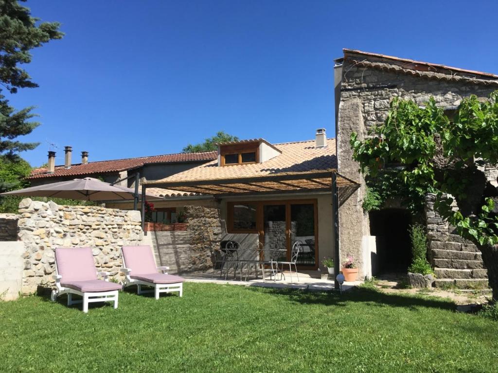 - deux chaises roses dans la cour d'une maison en pierre dans l'établissement Gites "Oustaou de Bourboul", à Grospierres