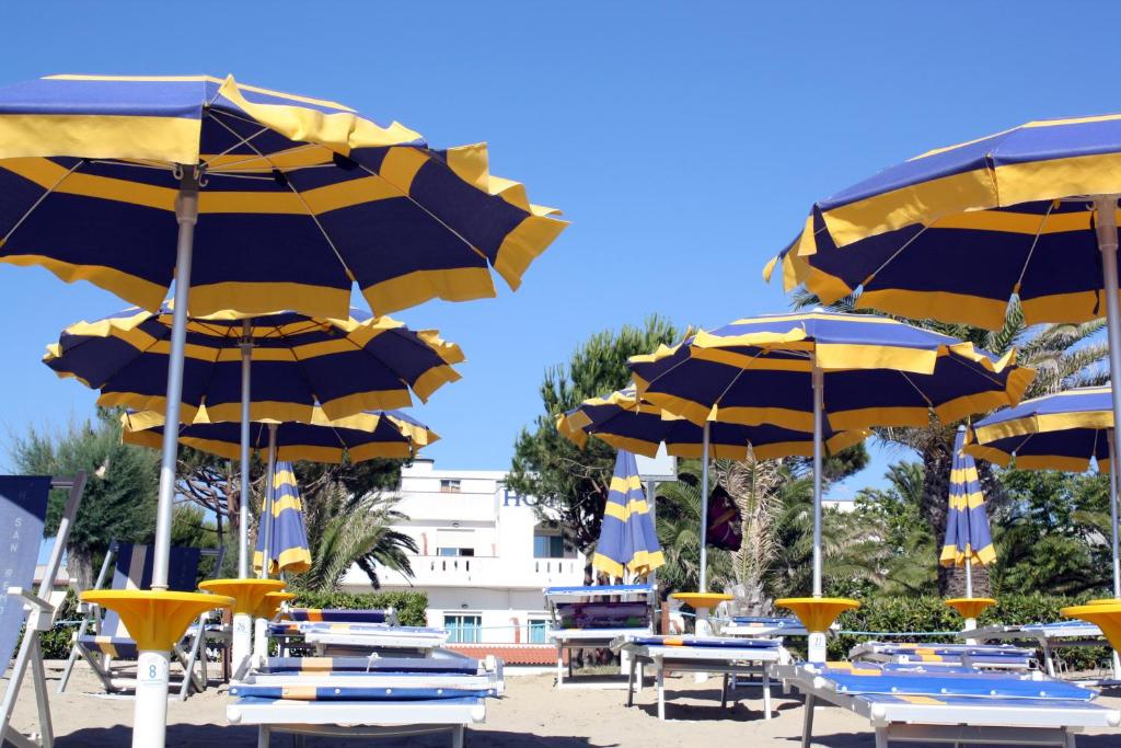 un groupe de parasols bleus et jaunes sur une plage dans l'établissement Hotel San Remo - All Inclusive - Fronte Mare - Spiaggia Privata, à Martinsicuro