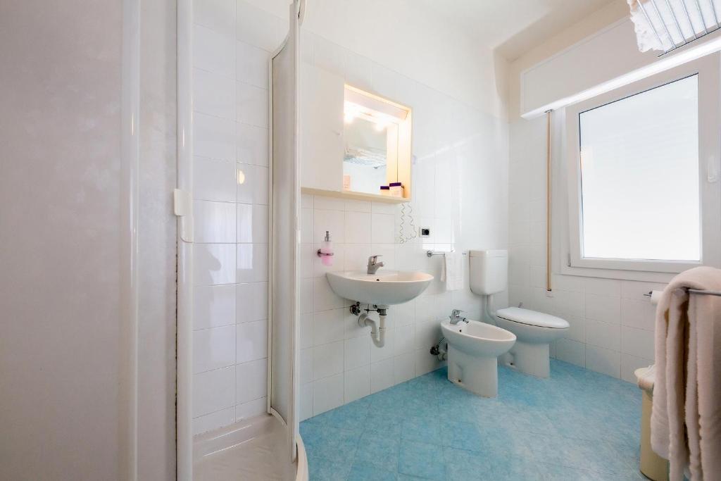 une salle de bain blanche avec un lavabo et des toilettes dans l'établissement Hotel Maxim, à Caorle