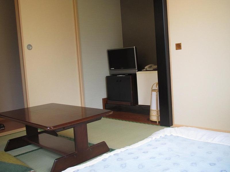 un salon avec une table et une télévision dans l'établissement Ryokan Fuji, à Tokyo