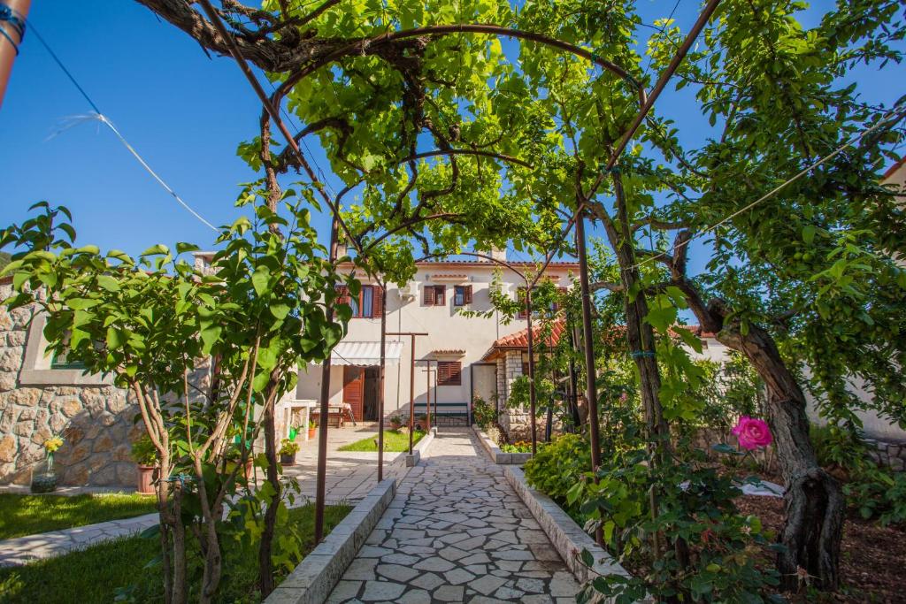 a garden path with trees and a house in the background at Rooms Kučić in Cres