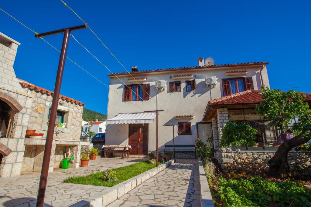 a house with a stone walkway in front of it at Rooms Kučić in Cres