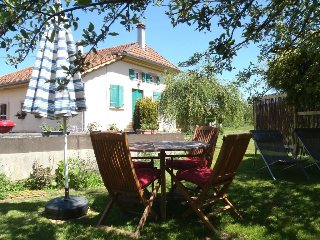 una mesa y sillas en el patio de una casa en Gite du gros pommier en Saulxures