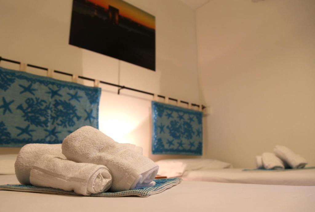 een stapel handdoeken bovenop een bed bij Antica Pensione Pinna in Castelsardo