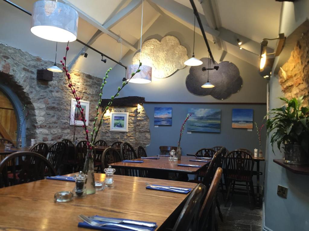 uma sala de jantar com mesa, cadeiras e luzes em The George Inn em Wells