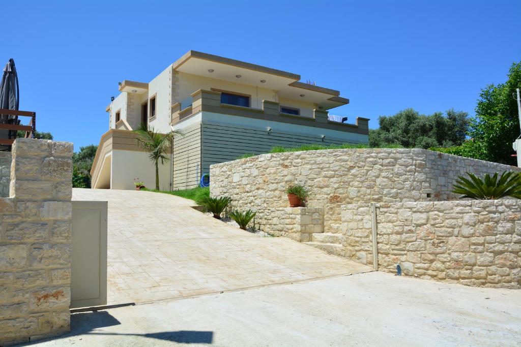 uma casa com uma parede de pedra e um edifício em Villa Ikaros em Kalamitsi Amygdali