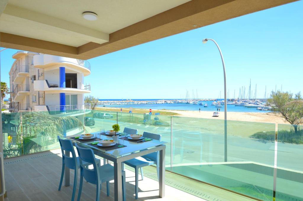 a table and chairs on a balcony with a view of the beach at Yachting Apartment in Marzamemi