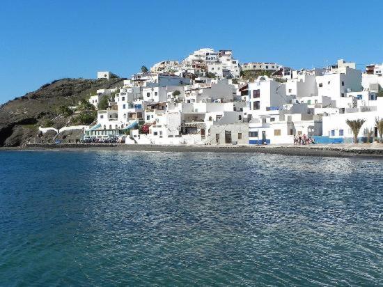 a group of white buildings on a hill next to the water at Casa Gaia in Las Playitas