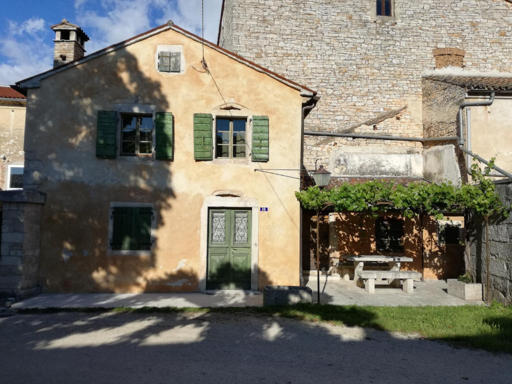 un vieux bâtiment avec une porte verte et un banc dans l'établissement Kuća za odmor - Ferlin, à Svetvinčenat