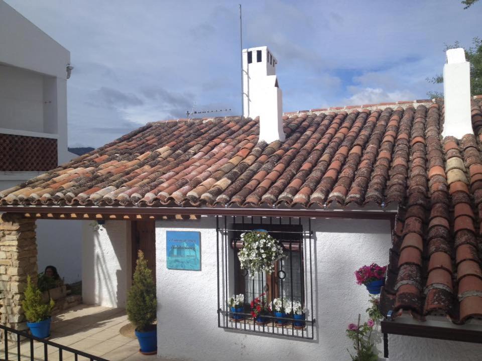 a white house with a tile roof with a window at El rincon de Paco in Segura de la Sierra