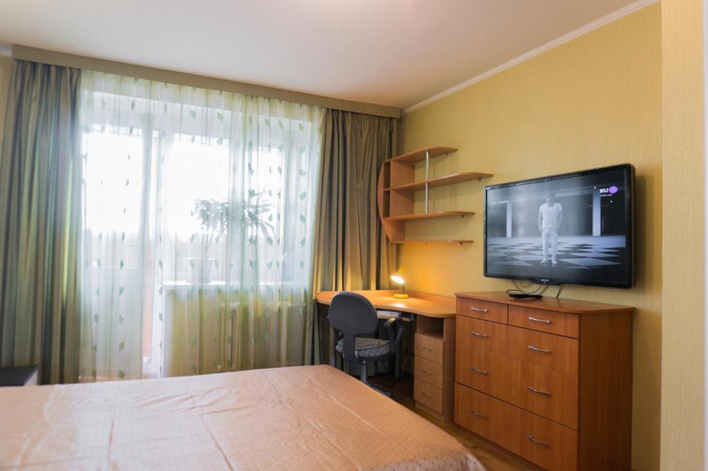 キーロフにあるApartments in Kirov on Maklinaのベッド、デスク、テレビが備わるホテルルームです。