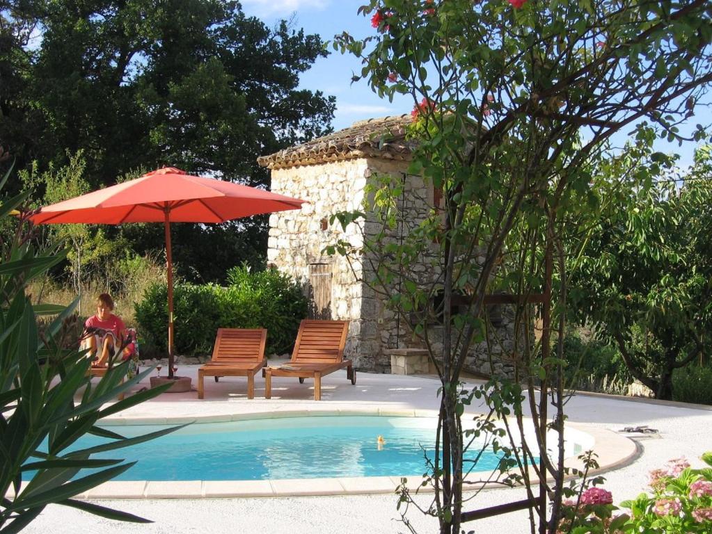 une femme assise sous un parasol à côté d'une piscine dans l'établissement Pierre de Lune, à Fox-Amphoux