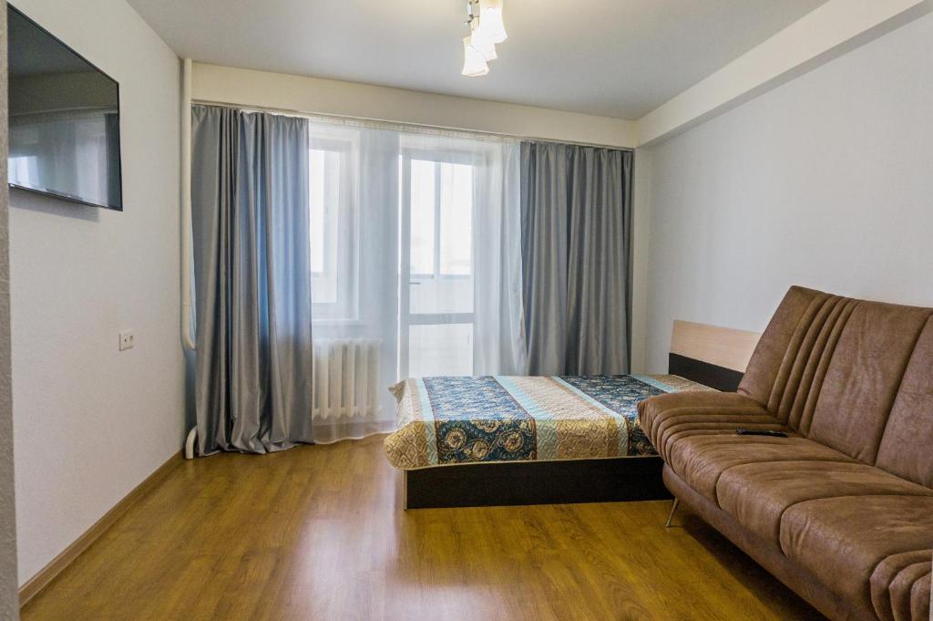 キーロフにあるApartamenty na Gorkogo 25のソファ、ベッド、窓が備わる客室です。