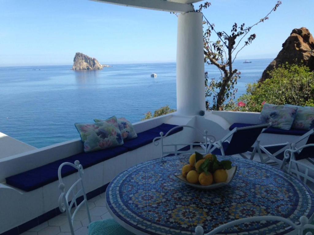 a table with a bowl of fruit on a balcony overlooking the ocean at Casa Prete in Panarea