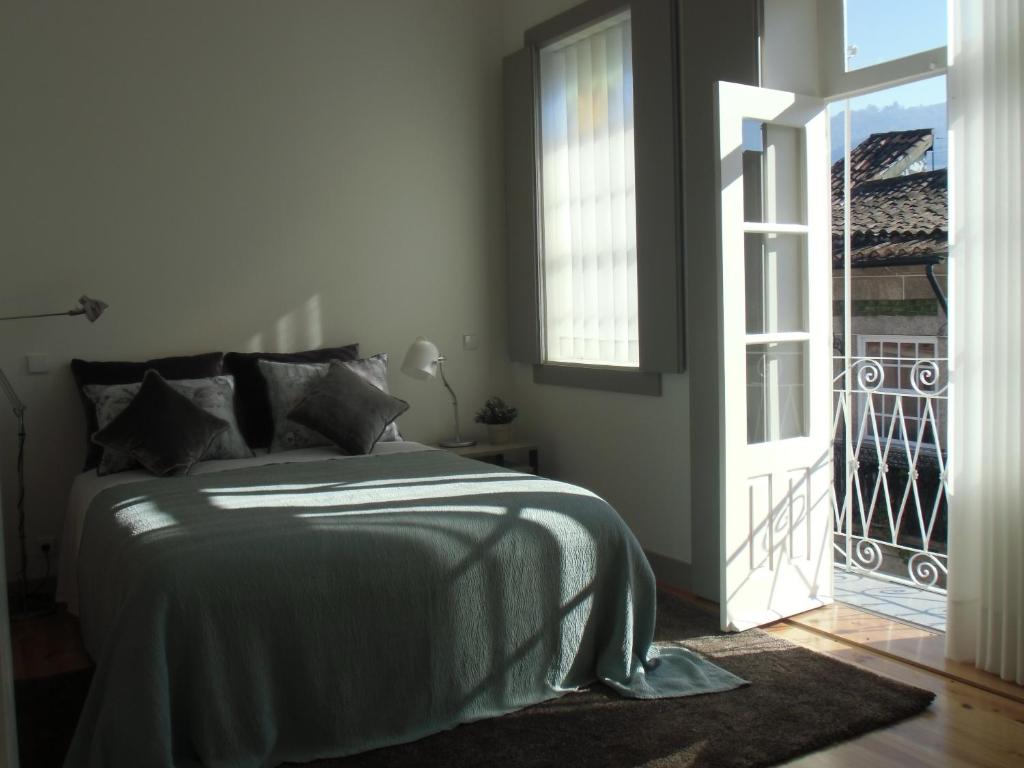 um quarto com uma cama e uma porta para uma varanda em Vila Baixa - alojamento local em Guimarães