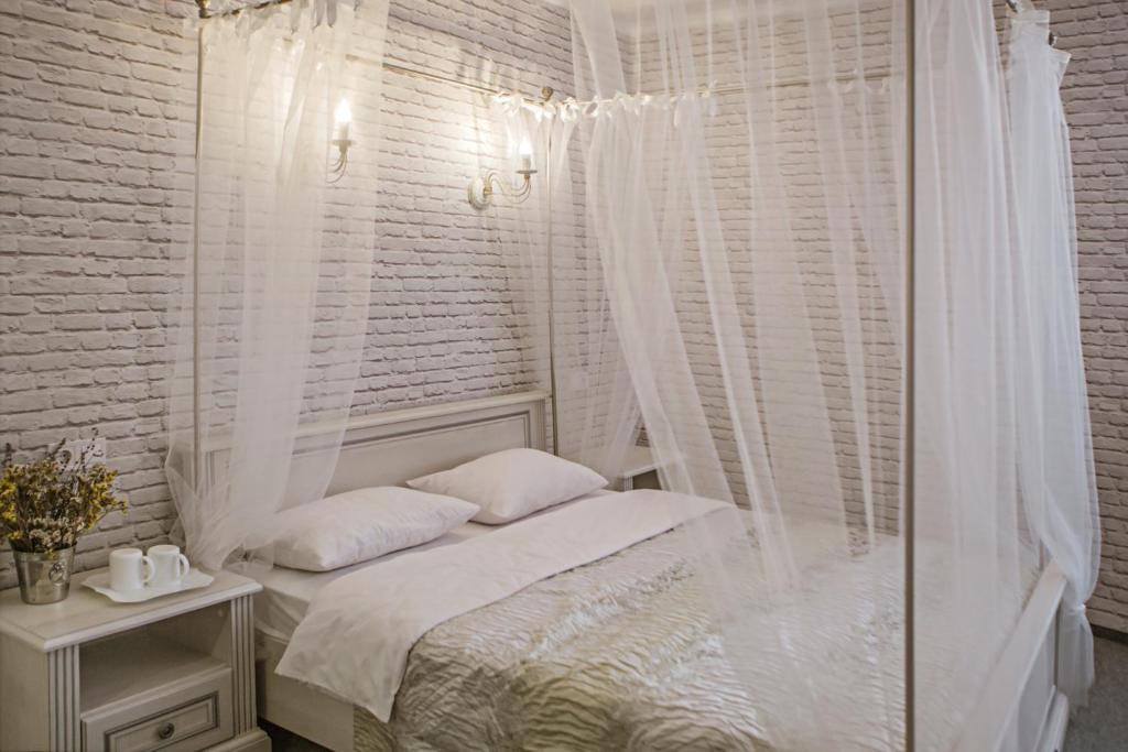 a white bedroom with a canopy bed and a window at Mini Hotel Ryleev in Kharkiv