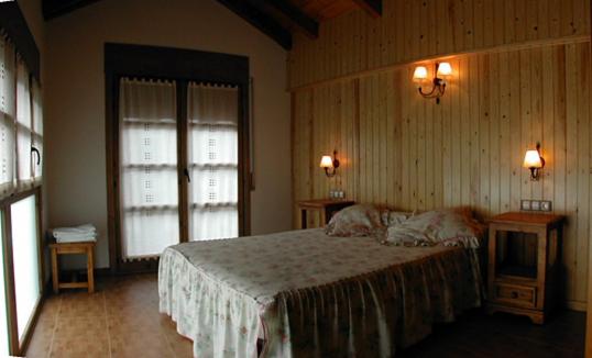 a bedroom with a bed and two tables and two windows at Gabarre in Broto