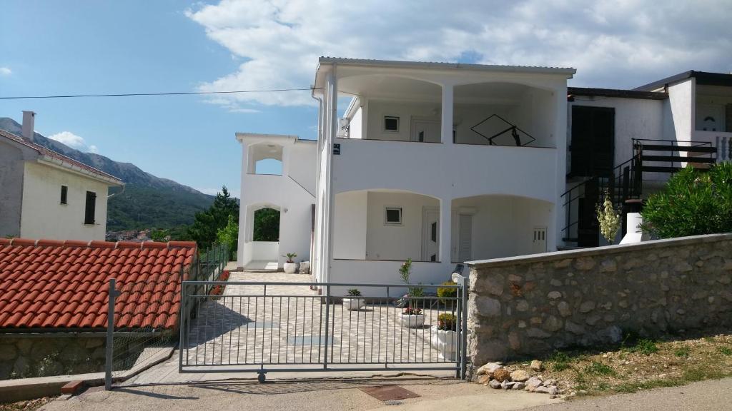 a white house with a fence in front of it at Ruza Apartmani in Draga Bašćanska