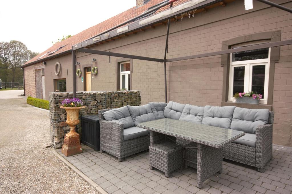 a patio with couches and a table and a building at B&B Crijbohoeve stallen en weidegang voor paarden mogelijk in Zutendaal