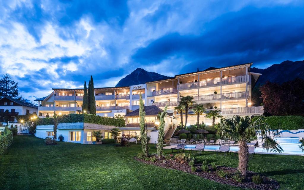 a hotel with palm trees in front of a building at Appartementhaus Residence Hirzer in Tirolo