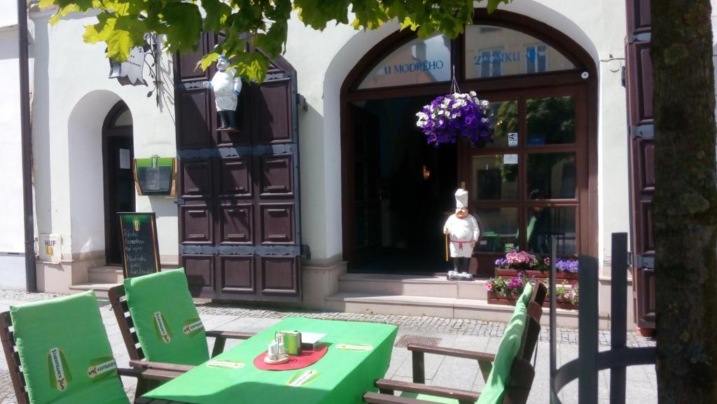 a green table and chairs in front of a building at Penzion u modrého zvonku in Zlaté Hory