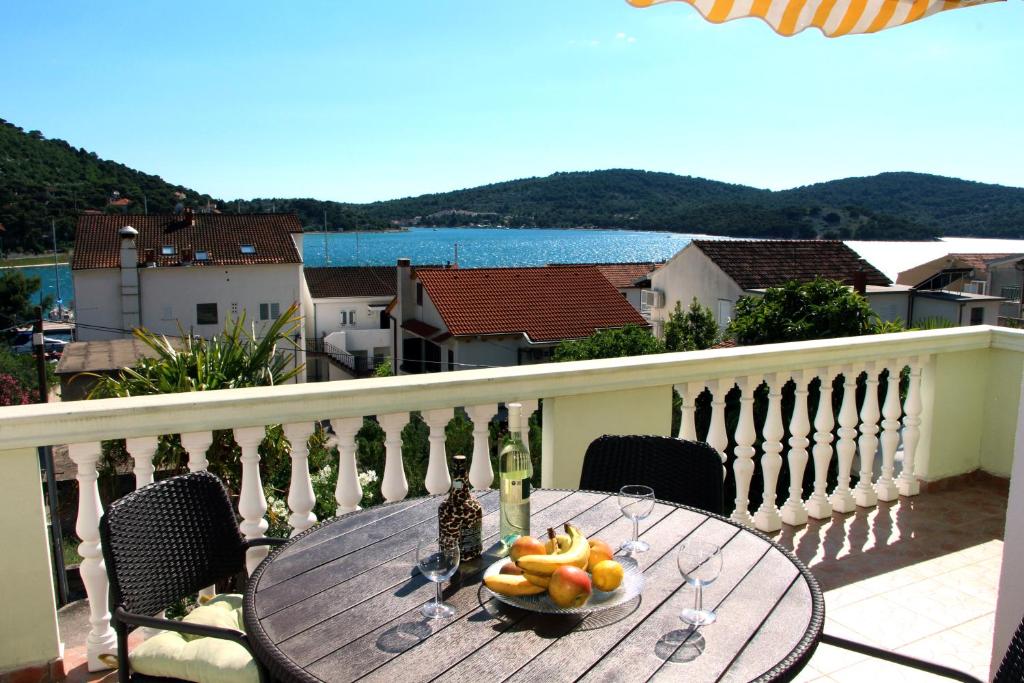 a table with a bowl of fruit on a balcony at Apartments Villa Russo in Tisno