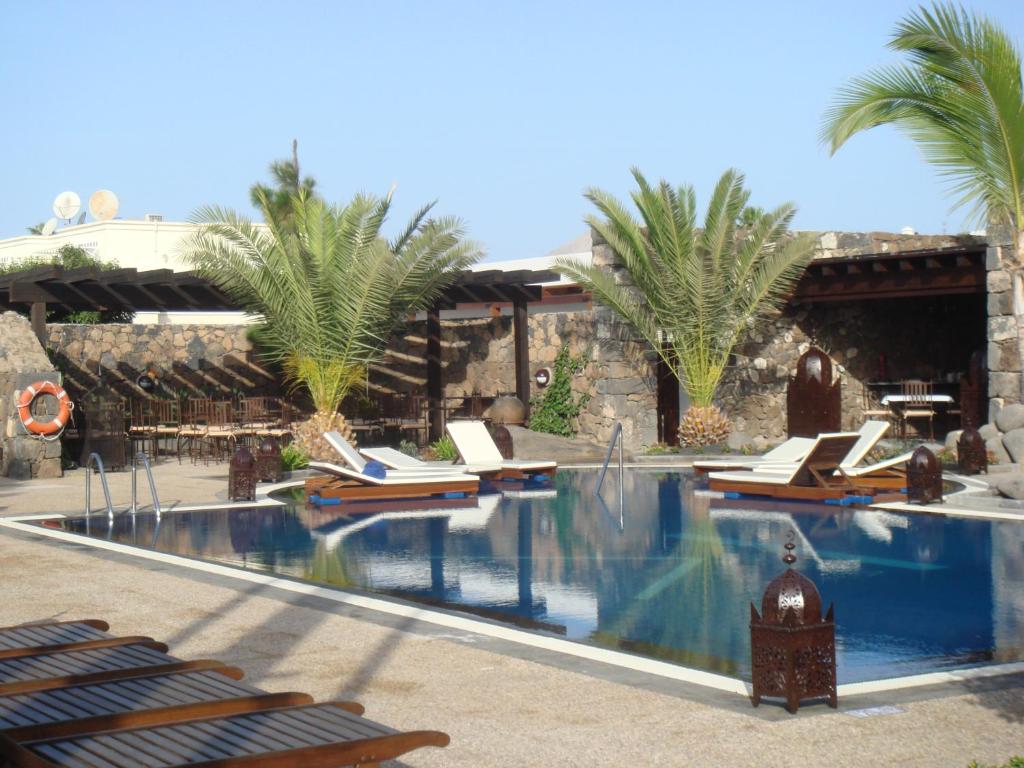 a swimming pool with a resort with palm trees at Villa VIK - Hotel Boutique in Arrecife
