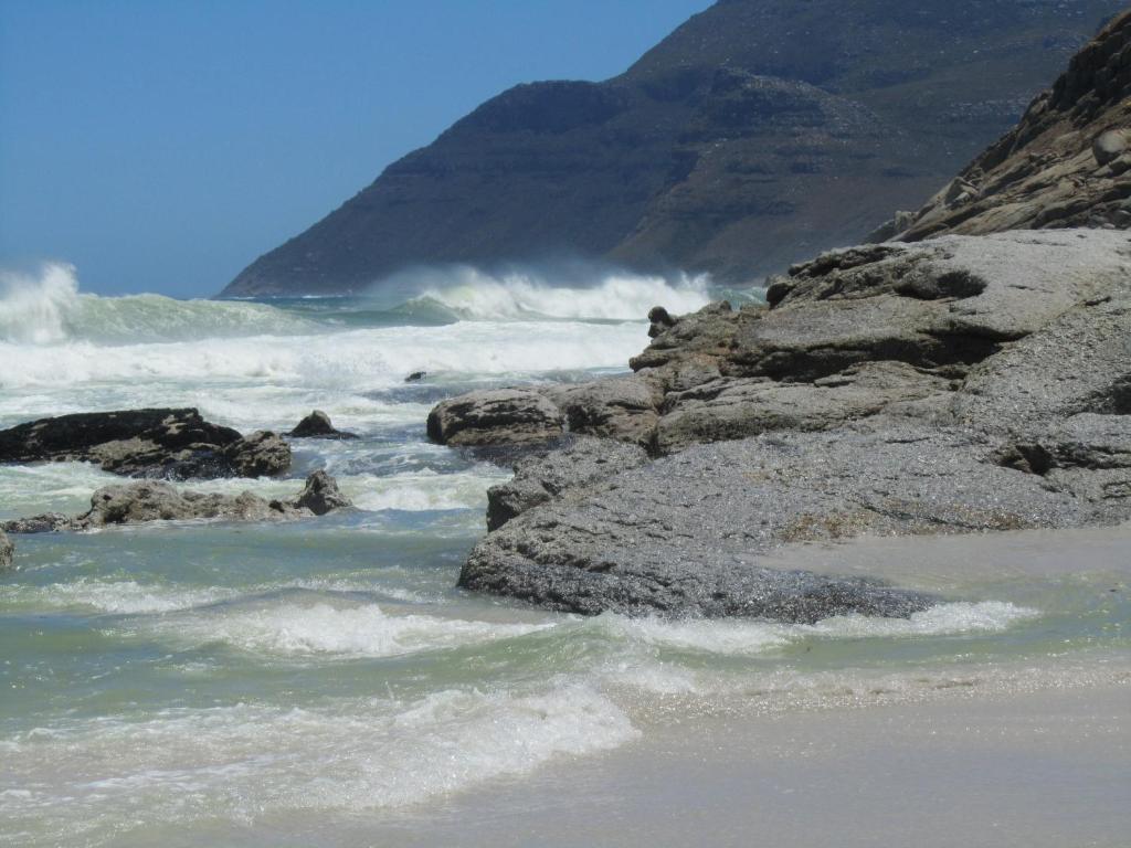 a beach with rocks and waves in the ocean at Brynbrook House in Noordhoek