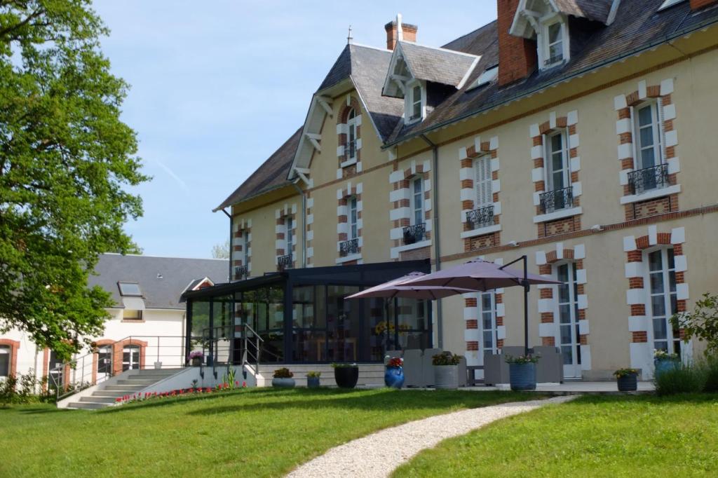 a large building with an umbrella in front of it at Domaine de Croix en Sologne in Neuvy-sur-Barangeon