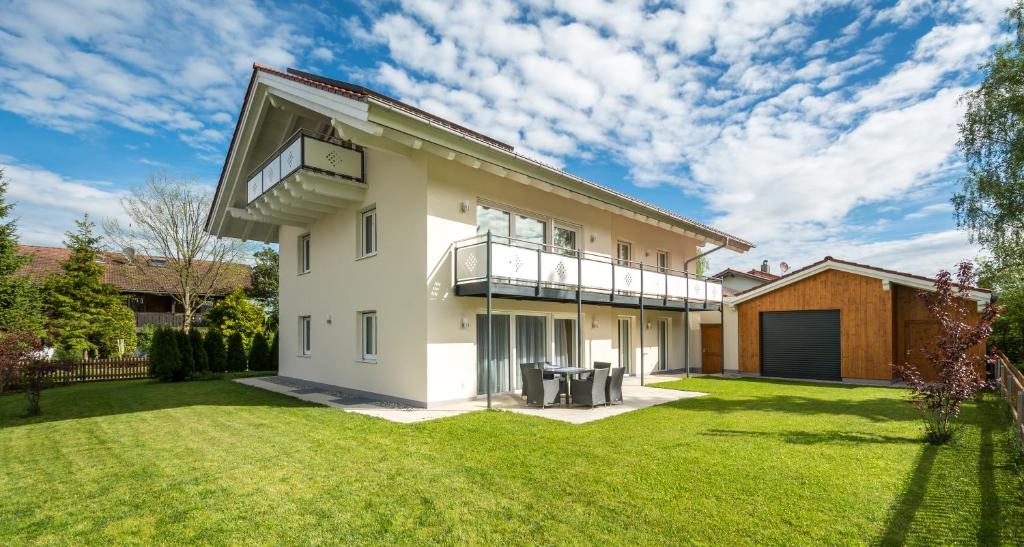a house with a balcony and a lawn at Ferienhaus Villa Alpenpanorama in Ohlstadt