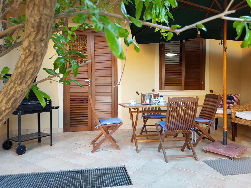 a patio with chairs and a table and an umbrella at La dimora del capitano in San Vito lo Capo