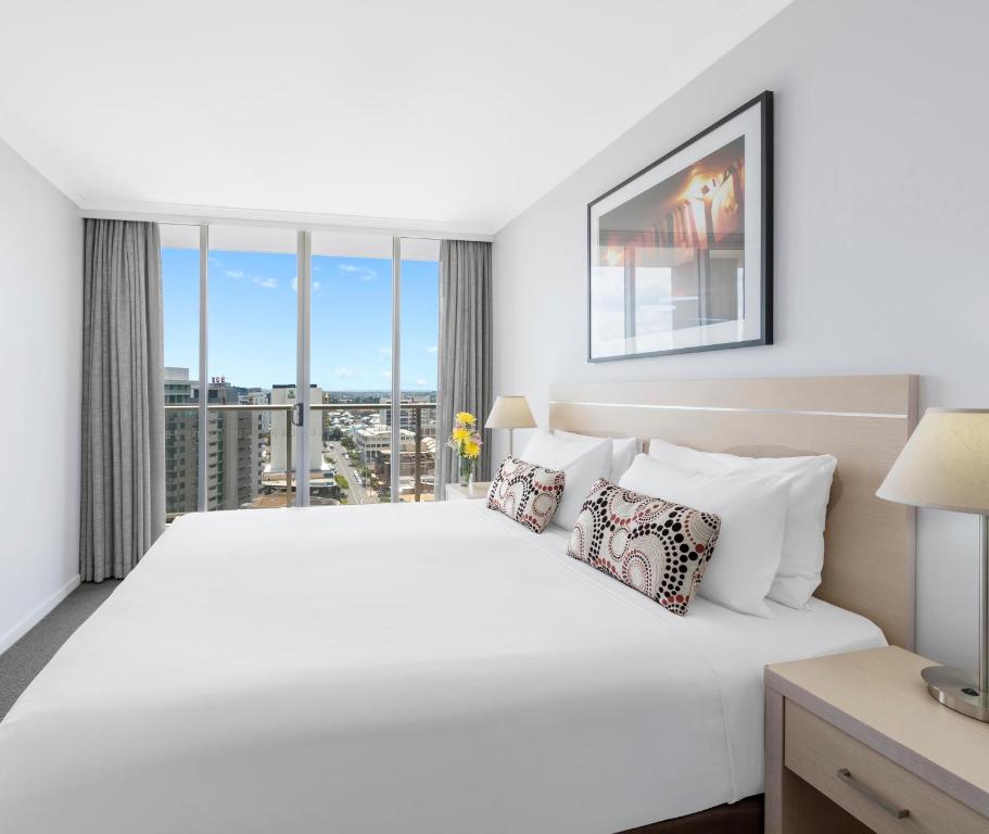 a hotel room with a large bed and a large window at Oaks Brisbane Lexicon Suites in Brisbane