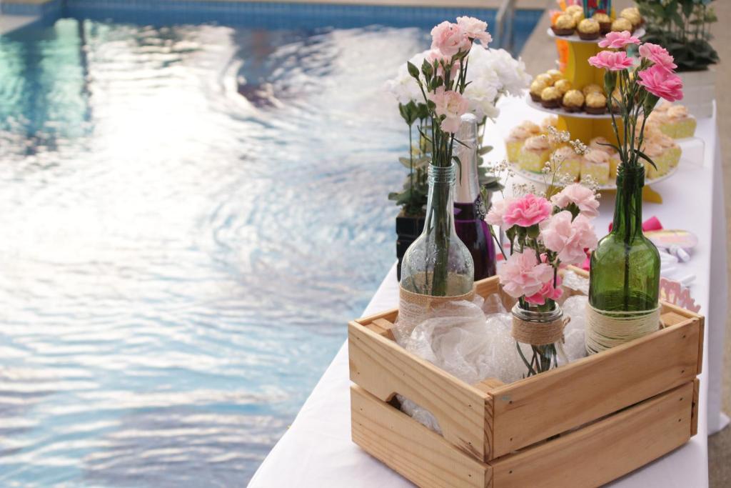 een tafel met flessen en bloemen in een krat naast een zwembad bij Paradise Spa Hotel in Port Dickson