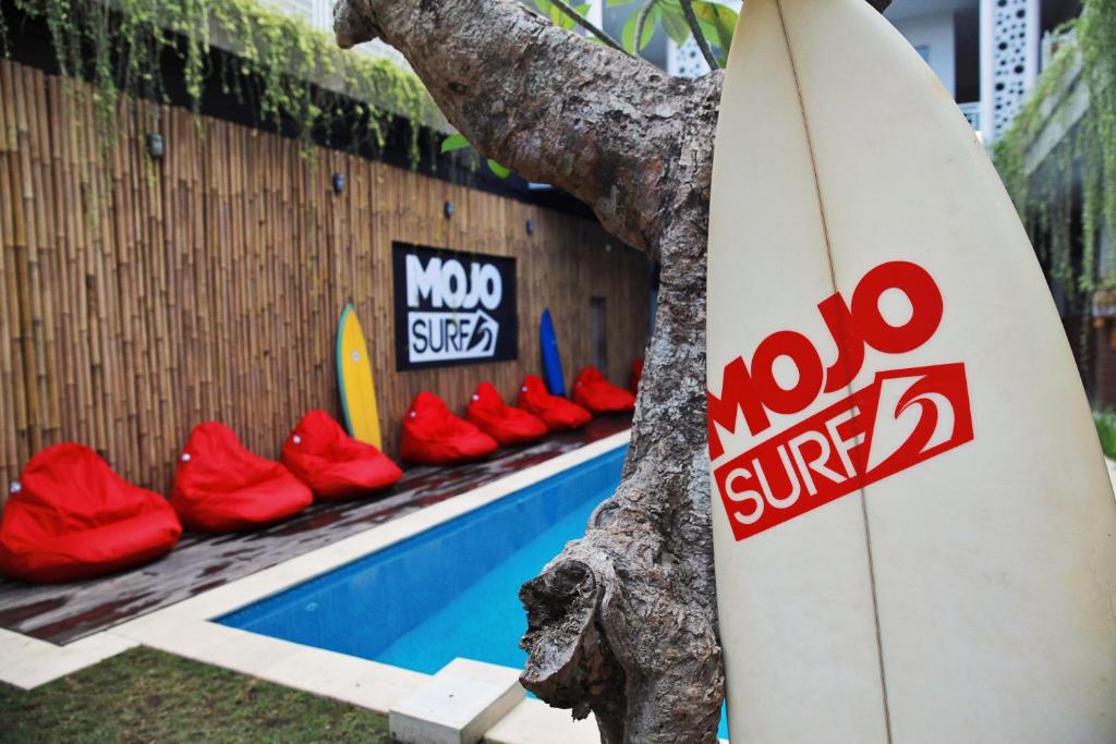 a surfboard sitting next to a tree next to a pool at Mojosurf Camp Canggu in Canggu