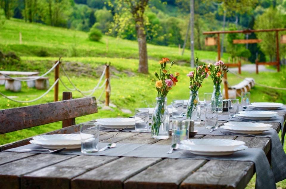 una mesa de madera con platos y flores en jarrones en Rancho Panderoza en Duszniki Zdrój