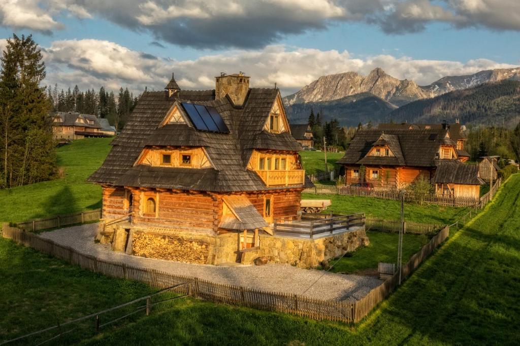 a large log house with mountains in the background at Willa Giewontka in Witów