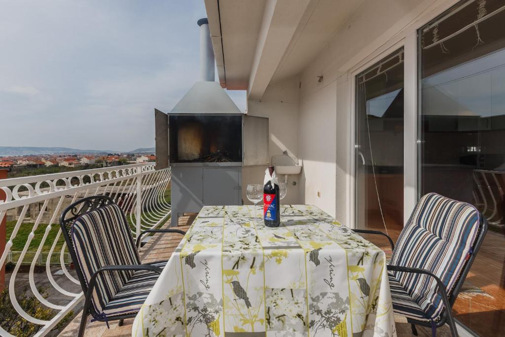 einen Tisch mit Stühlen und eine Flasche auf dem Balkon in der Unterkunft Apartment Lena in Kaštela