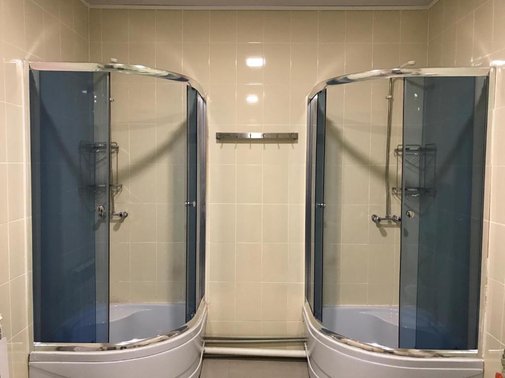 a bathroom with two shower stalls with mirrors at Bereke Hostel in Shymkent