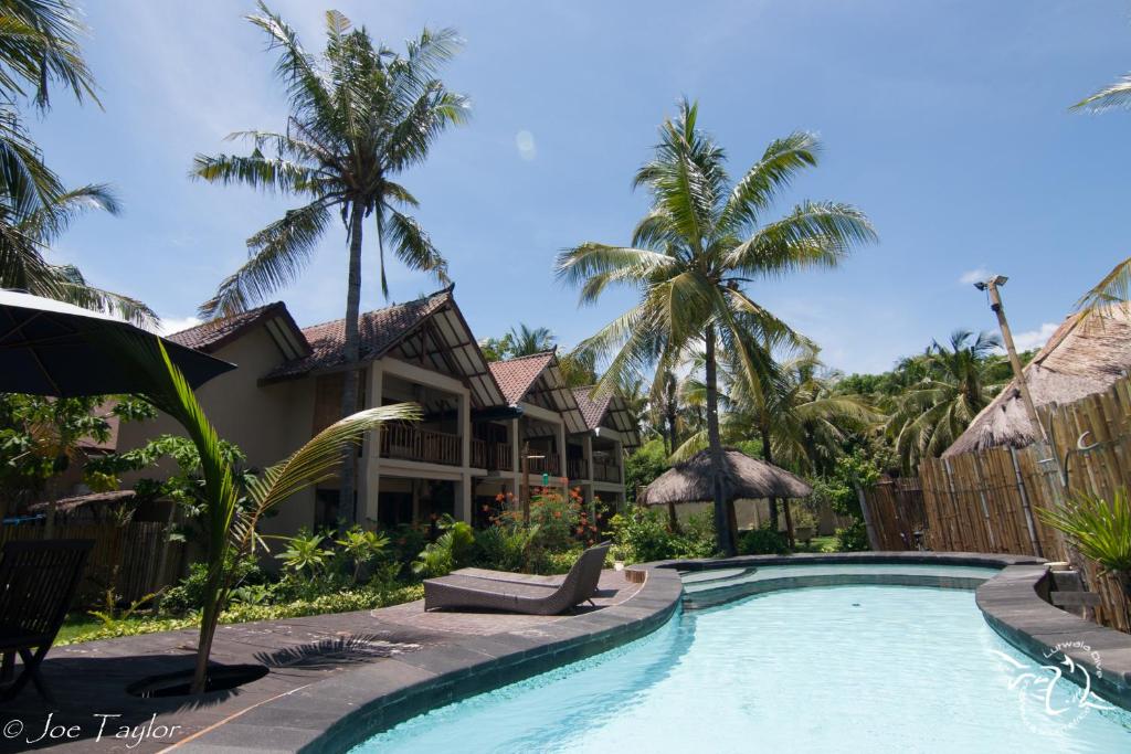 a swimming pool in front of a resort with palm trees at Lutwala Bungalows and Private Villa in Gili Trawangan