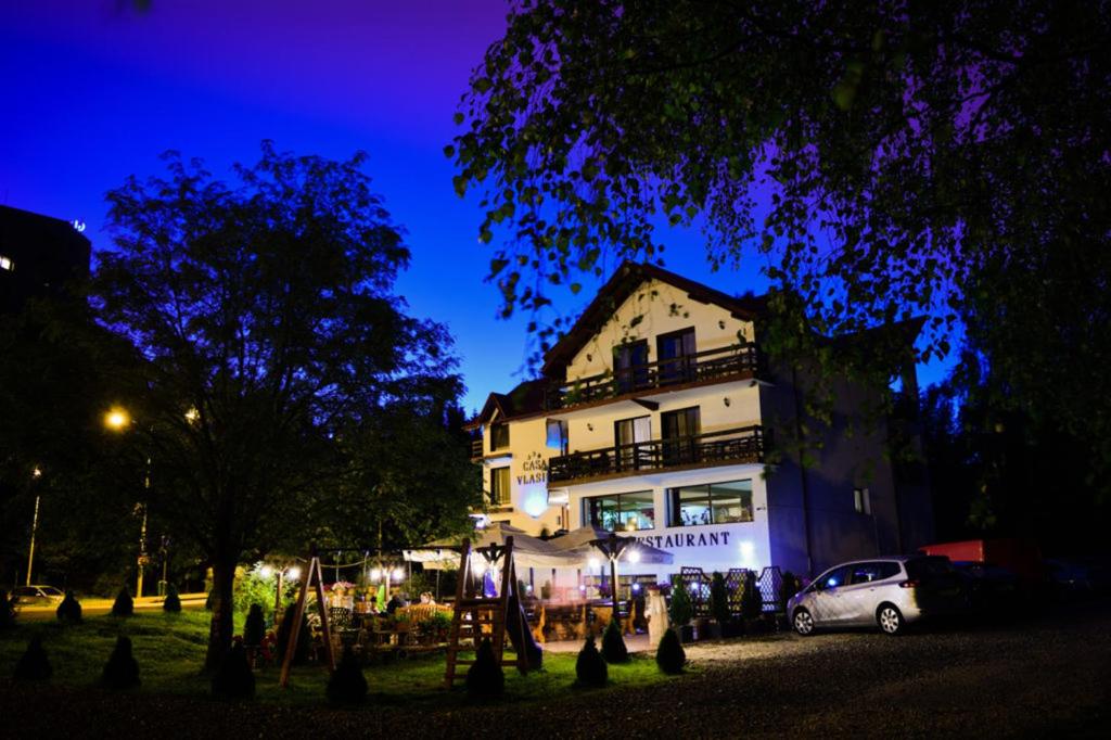 un edificio con auto parcheggiate di fronte ad esso di notte di Casa Vlasin a Poiana Brasov