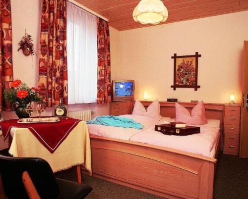 a bedroom with a bed and a table and a television at Hotel Post in Nordhalben