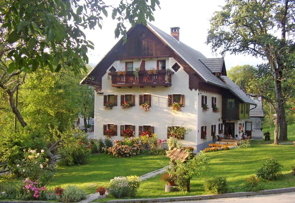 a white house with a balcony on a yard at Farm Pri Flandru in Cerkno