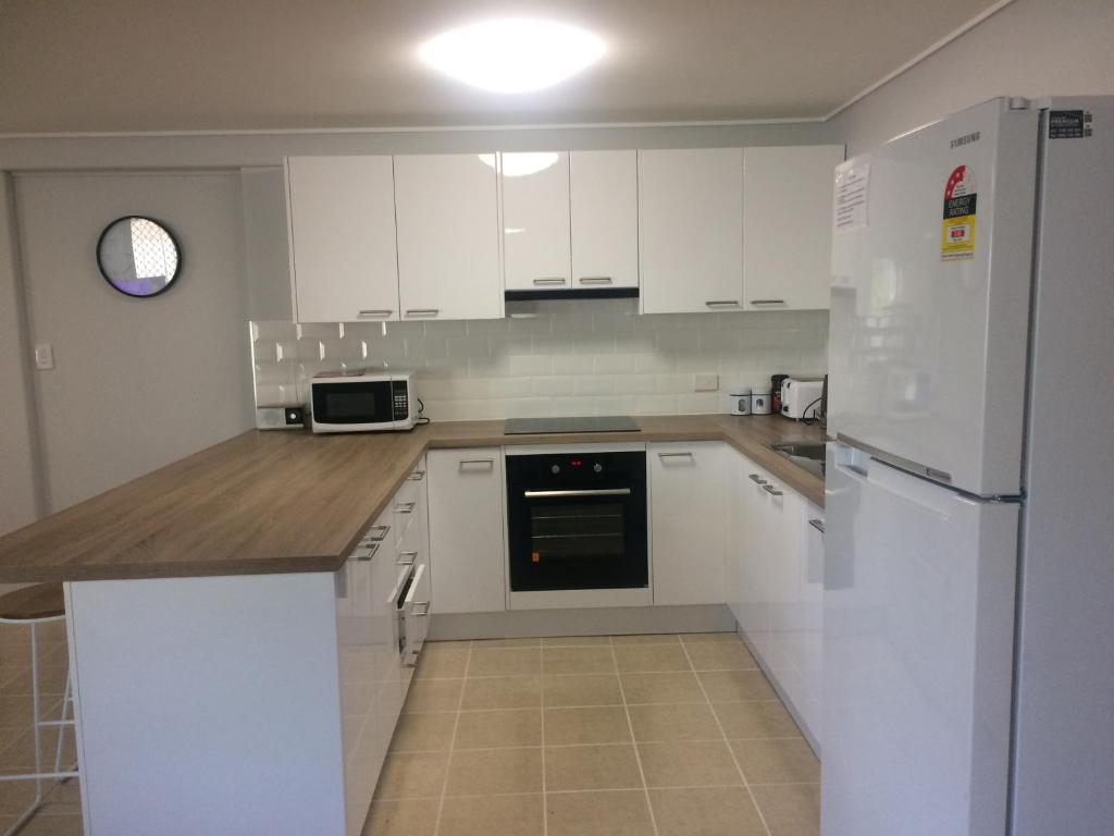 uma cozinha com armários brancos e um frigorífico branco em Stretton Lane em Townsville