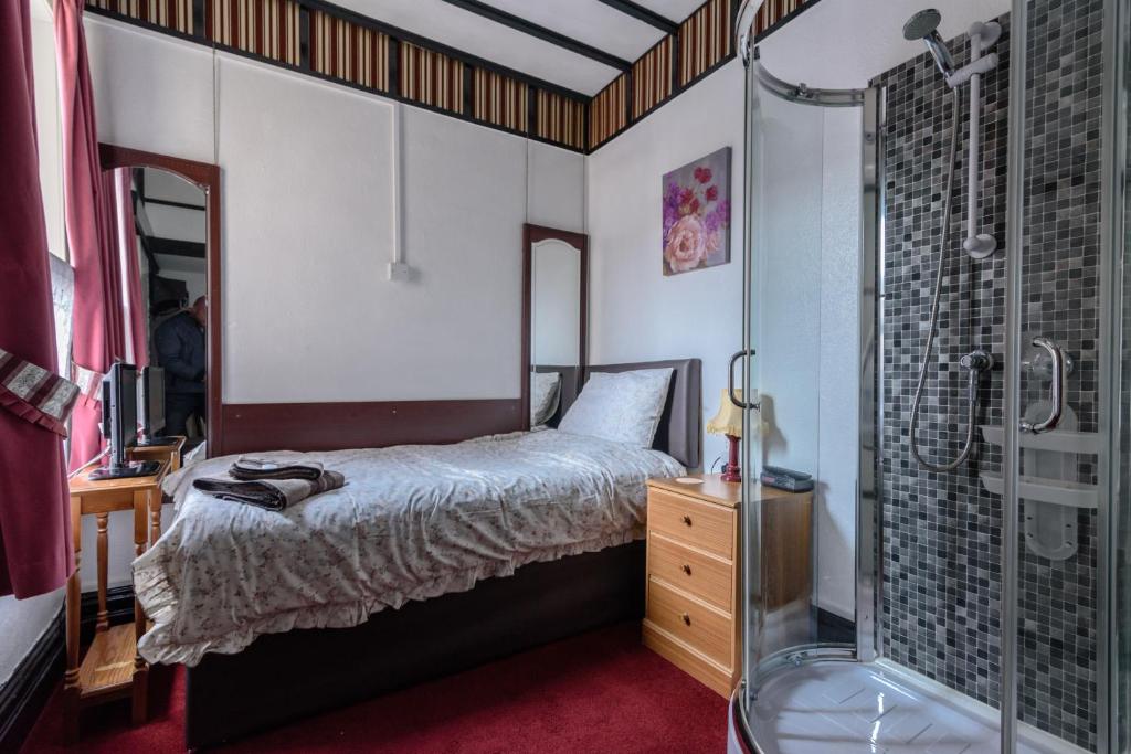 1 dormitorio con 1 cama y ducha acristalada en Happy Days Guesthouse, en Bridlington