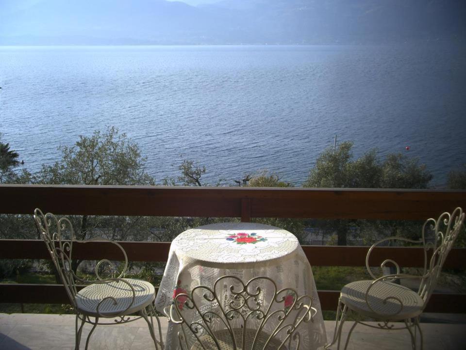 a table and chairs on a balcony overlooking the water at Casa Miralago in Torri del Benaco