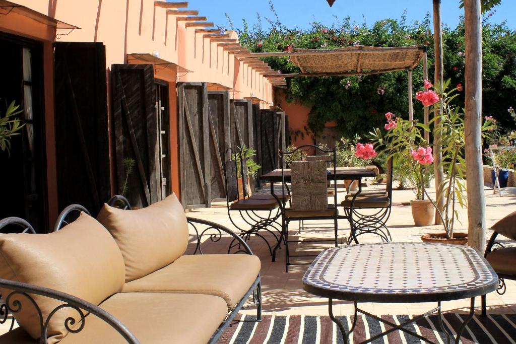 eine Terrasse mit einem Sofa, Tischen und Stühlen in der Unterkunft Maison Marocaine Agadir in Agadir