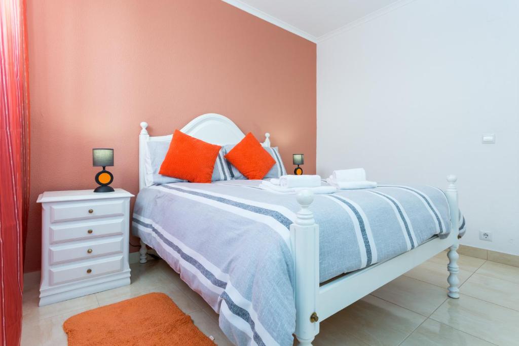 um quarto com uma cama branca e almofadas laranja em Apartamento Arenga em Lagos